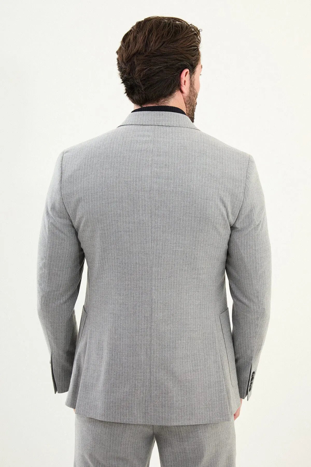 Men’s gray slim-fit mono-collar (mandarin collar) performance suit with 2-button single-breasted jacket, minimalist patch pockets, matte micro-texture fabric, styled with a black turtleneck.