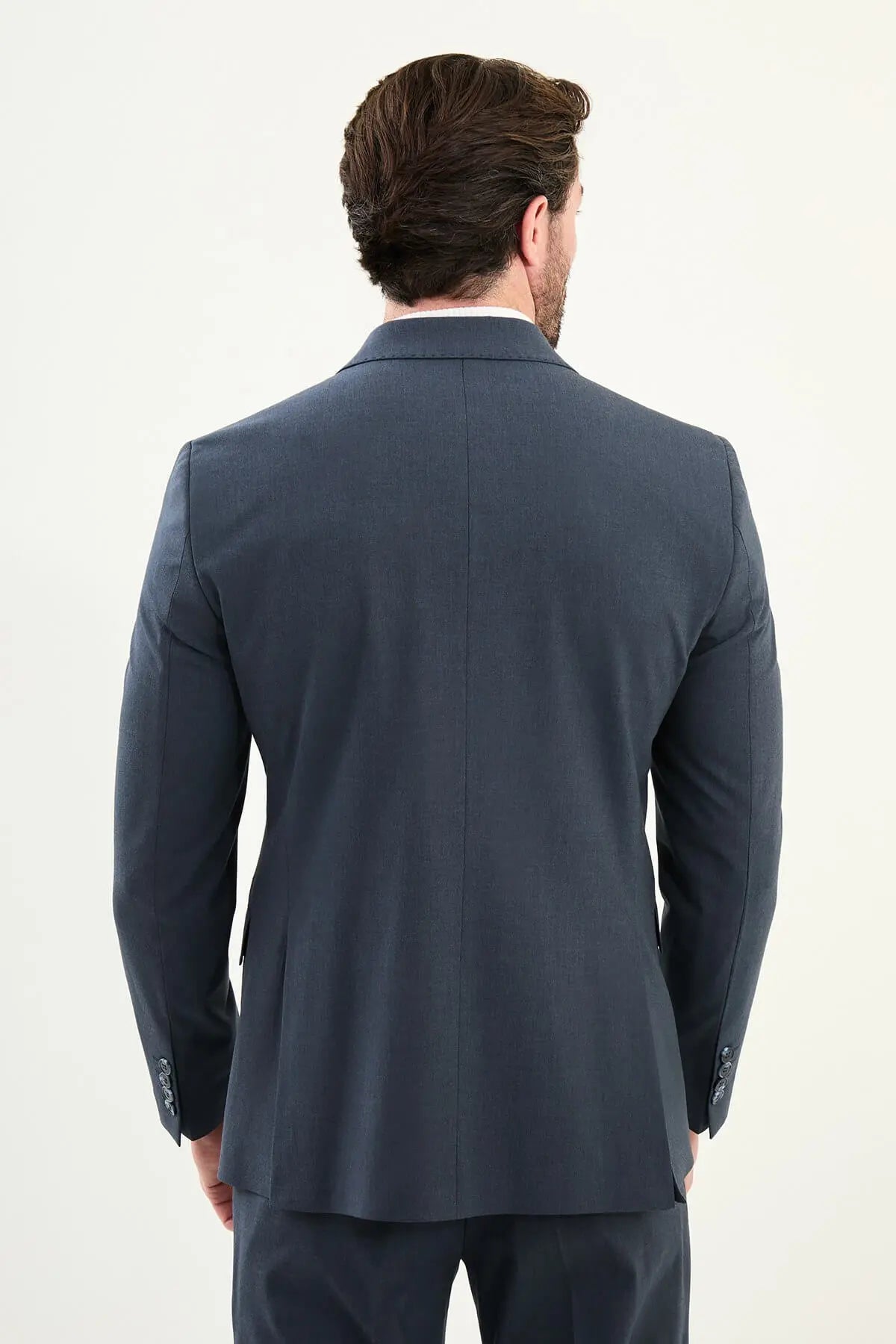Men’s navy blue slim-fit double-breasted 6x2 suit with peak lapels, matte micro-texture finish, cotton-wool-viscose blend with stretch for wrinkle-resistant wear, styled with a white turtleneck.