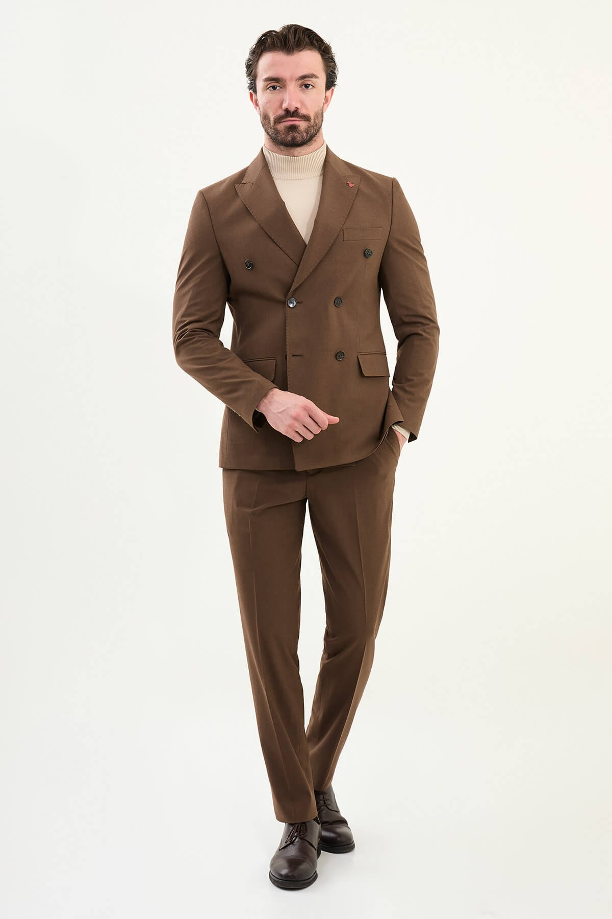 Men’s deep brown slim-fit double-breasted 6x2 suit with peak lapels and patch pockets, cotton-wool-viscose blend with 4-way stretch for wrinkle-resistant wear, styled with a cream turtleneck.