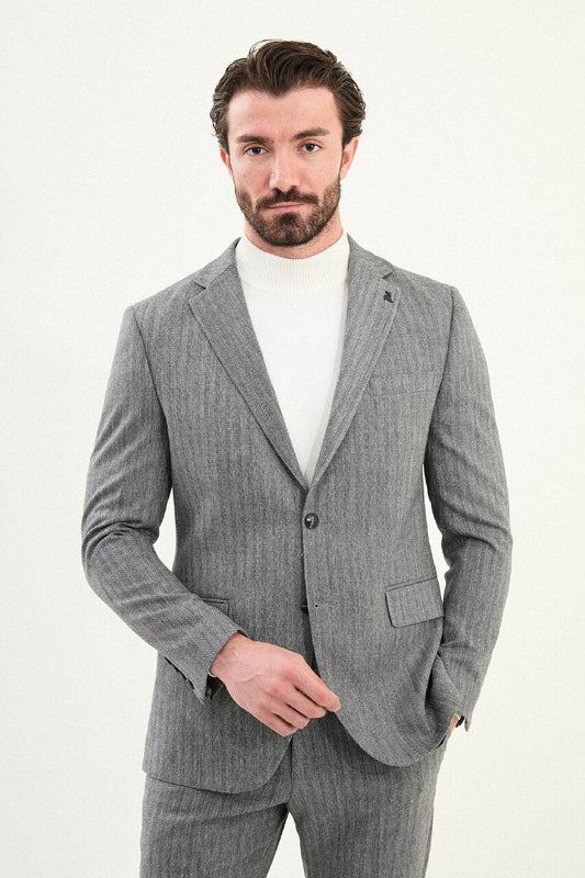 Men’s gray herringbone slim-fit single-breasted suit with structured shoulders and tailored waist, high-wool blend fabric with stretch, styled with a light gray fine-gauge turtleneck for winter.