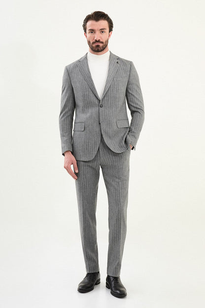 Men’s gray herringbone slim-fit single-breasted suit with structured shoulders and tailored waist, high-wool blend fabric with stretch, styled with a light gray fine-gauge turtleneck for winter.