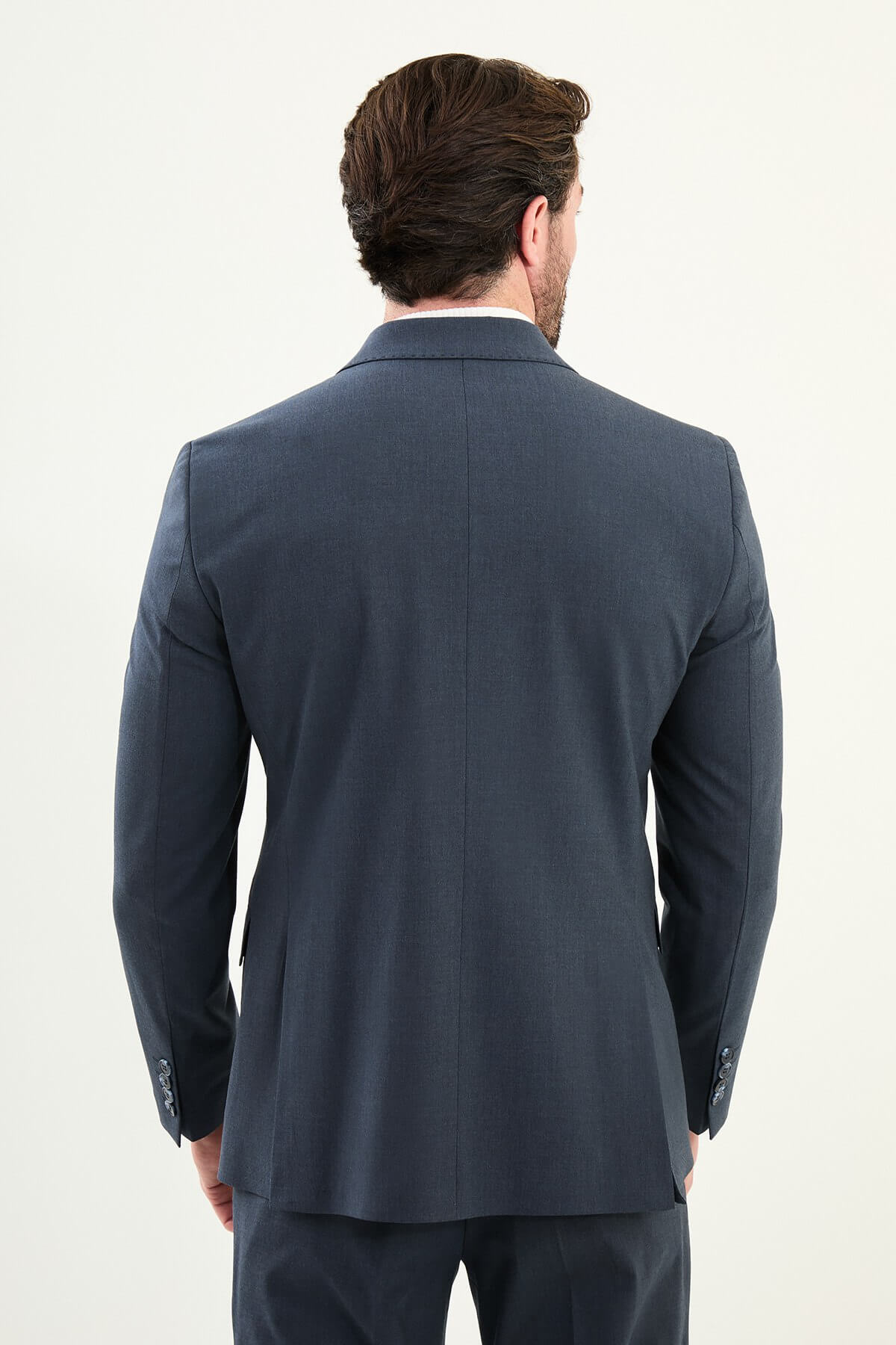 Men’s navy blue slim-fit double-breasted 6x2 suit with peak lapels, matte micro-texture finish, cotton-wool-viscose blend with stretch for wrinkle-resistant wear, styled with a white turtleneck.